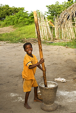 Young boy crushing maize in Guludo village in the Quirimbas National Park in northern Mozambique, Africa