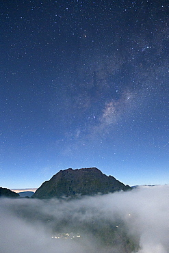 Night-time view of a mountain peak poking above the clouds on the French island of Reunion in the Indian Ocean, Africa