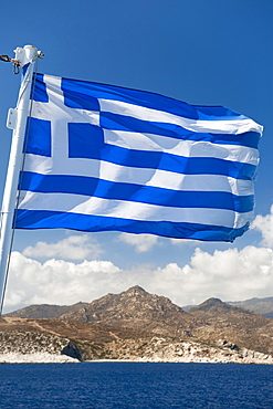 Greek flag seen against a view of Naxos island, Cyclades, Greek Islands, Greece, Europe