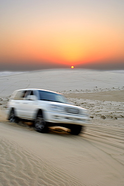 A 4X4 at the Inland Sea (Khor al Adaid) in southern Qatar at sunset. 