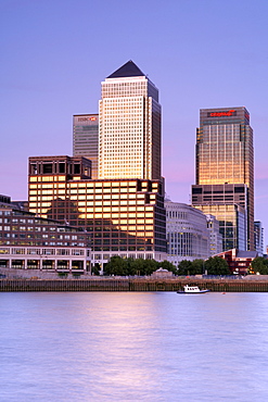 Dusk view across the Thames River of Canary Wharf Tower and other buildings in the docklands on the Isle of Dogs in London. Canary Wharf Tower is the tallest building in Britain and the architect was Cesar Pelli.