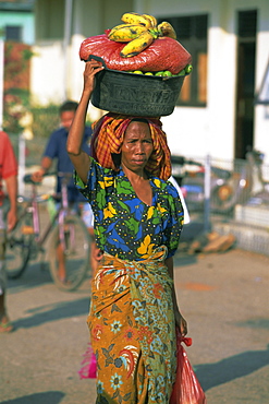 Woman carrying basket of fruit on her head, Sape, Sumbawa, Nusa Tenggara group, Indonesia, Southeast Asia,  Asia