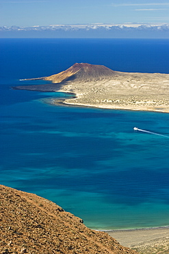 Volcanic cinder cone on Graciosa Island and the Graciosa to Lanzarote ferry in the Rio strait, seen from the Mirador del Rio on the north west coast of Lanzarote, Graciosa Island, Canary Islands, Spain, Atlantic, Europe