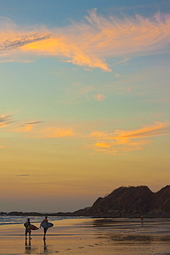 Surfers at sunset on Playa Guiones surf beach, Nosara, Nicoya Peninsula, Guanacaste Province, Costa Rica, Central America