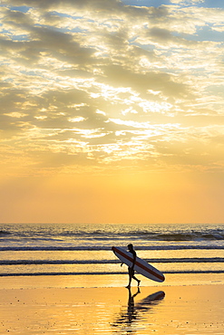 Surfer with long board at sunset on popular Playa Guiones surf beach, Nosara, Nicoya Peninsula, Guanacaste Province, Costa Rica, Central America