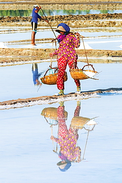 Woman with shoulder pole harvesting the salt fields around the Praek Tuek Chhu River estuary south of the city, Kampot, Cambodia, Indochina, Southeast Asia, Asia