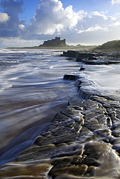 Surf on rocks, Bamburgh Castle, Northumberland, England, United Kingdom, Europe