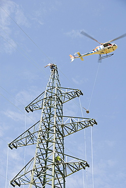 Helicopter connecting power lines, worker on an electricity pylon reaching for the cable, Waldviertel, Forest Quarter, Austria, Europe