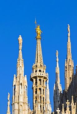 Madonnina statue on cathedral spire against blue sky, Milan city, Italy, Europe