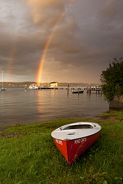 Red boat on Lake Constance in front of a pier with a rainbow on the horizon, Baden-Wuerttemberg, Germany, Europe