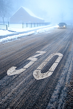 Slip hazard in a traffic calmed area, snow slush on a wintery road with fog, Borken, Gemen district, Muensterland, North Rhine-Westphalia, Germany, Europe