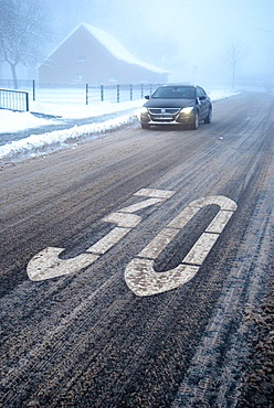 Slip hazard in a traffic calmed area, snow slush on a wintery road with fog, Borken, Gemen district, Muensterland, North Rhine-Westphalia, Germany, Europe