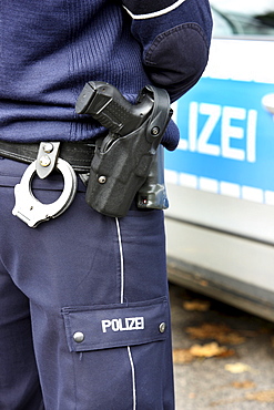 Police, police car, police officer with handcuffs and service weapon, Walther P99, in the holster