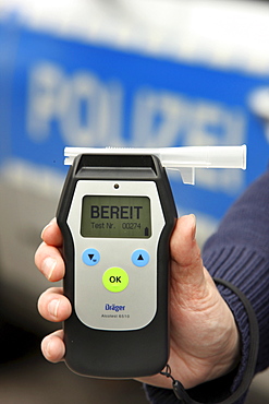 Police officer with breathalyser for checking the fitness to drive