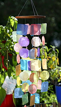 Colourful wind chime made of coloured plastic, hanging outside on a balcony or a terrace