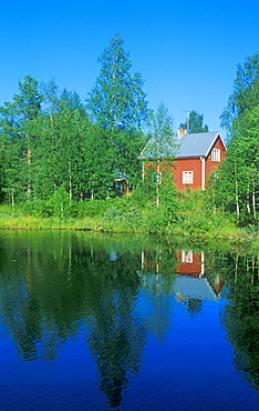 Typical red wooden house beside an idyllic lake near Saerna, Sweden, Scandinavia, Europe