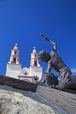 The Shrine of the Stations of the Cross, sculptures by artist Huberto Maestas, on a hill above town, the Chapel of All Saints at back, San Luis, Colorado, USA