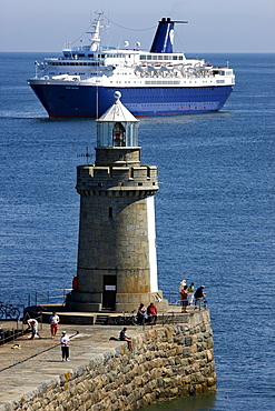 Cruise ship anchoring off the pier with lighthouse at Castle Cornet, port fortress, entrance to the port of St. Peter Port, Guernsey, Channel Islands, Europe