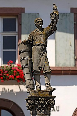 Wine-grower's fountain, statue of a wine-grower with grapes and a grape carrier, Grand'Rue, Ribeauville, Alsace, France, Europe