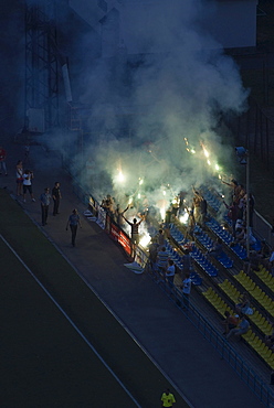 Football fans on tribune lighting fireworks