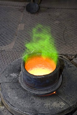 Bronze being heated in a melting pot on a gas stove in an art foundry