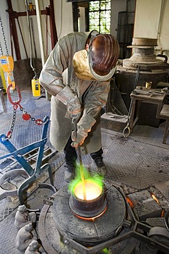 Bronze being heated in a melting pot on a gas stove in an art foundry