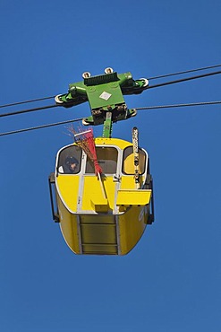 Yellow cabin of the Kampenwandbahn ropeway, with skis on the outside of the cabin and a witch's broom for carnival, Chiemgau, Bavaria, Germany, Europe