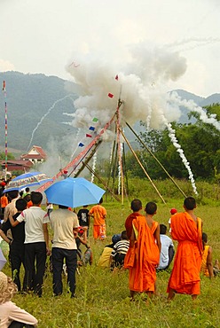 Festival, rocket firing, bang fai, launch and explosion of a rocket on the launch pad, monks in orange robes looking on, Muang Xai, Oudomxay province, Laos, Southeast Asia, Asia