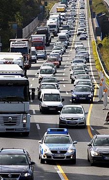 Police patrol car of the highway patrol weaving through a traffic jam to get to a car accident on the A2 highway, flashing lights and sirens, Germany, Europe