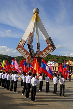 Festival, young men of the Lao Youth Organization carrying colourful flags in front of a monument, Xam Neua, Houaphan province, Laos, Southeast Asia, Asia