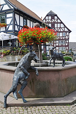 Fountain with sculptures of a wolf and a lamb on the market square with half-timbered houses, Wolfhagen, Habichtswald National Park, Hesse, Germany, Europe