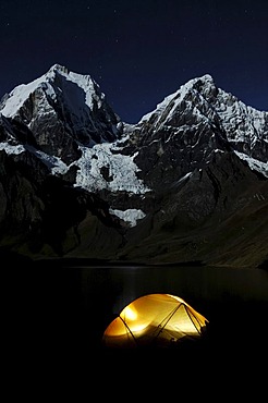 Tent glowing in the dark at Laguna Carhuacocha, Yerupacha, left, and Yerupacha Chico, behind, Cordillera Huayhuash, Peru, South America