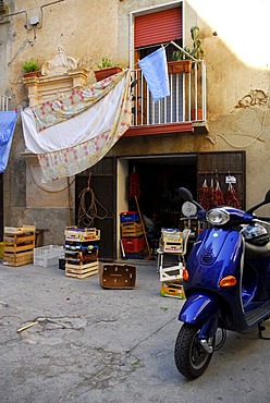 Blue motor scooter, small shop in an inner yard, washing hanging from a balcony, Tropea, Vibo Valentia, Calabria, South Italy, Europe