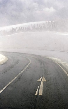 Wet lane and poor visibility in a curve on the road throug the Erzgebirge in winter, Erz Ore Mountains, Saxony, Germany