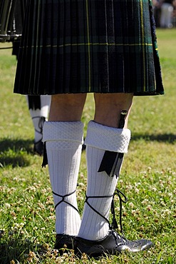 Scottish bagpiper in traditional kilt with a dirk in his woolen socks