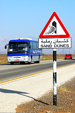 Road sign warning against encroaching sand dunes posted alongside the Wahiba Sands Desert, Ramlat al Wahaybah, Oman, Middle East