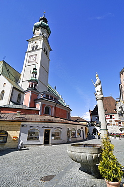 Church steeple and fountain in the cobbled streets of the upper town square in the historic centre of Hall, Tyrol, Austria