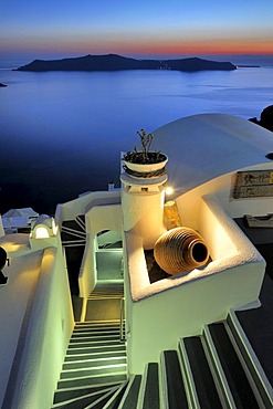 Illuminated stairway and a clay vase at sunset in front of the blue sea and the volcanic island of Nea Kameni, Thira, Fira, Santorini, Cyclades, Greece, Europe