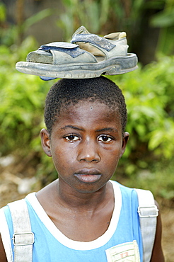 Boy balancing a shoe on his head, Cameroon, Africa