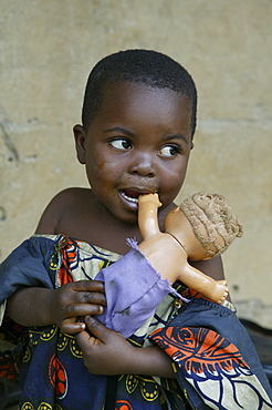 Young African girl holding a white doll, Cameroon, Africa