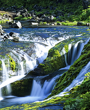 Small waterfall in a mountain stream with moss-covered rocks, Iceland