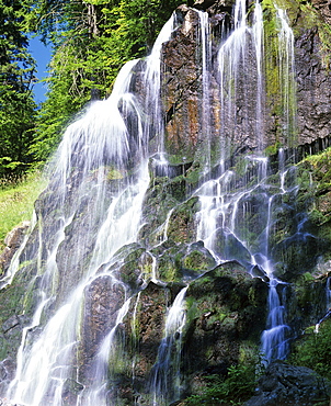 Waterfall in a mountain stream with moss-covered rocks. cascade