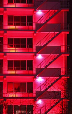 NLD, The Netherlands, Rotterdam: Fire escape stairs at a building, red illuminated. |