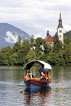 Excursion boat on Lake Bled in front of Assumption of Mary's Pilgrimage Church, Bled, Slovenia