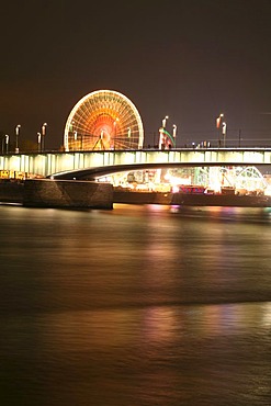 Deutzer bridge over the Rhine river and fair lights with the big wheel in Cologne, NRW, Germany