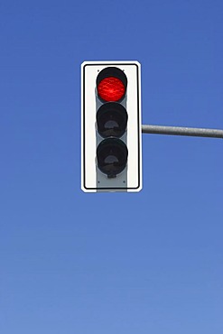 Red traffic light in blue sky