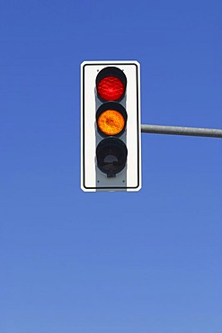 Red and yellow traffic light in blue sky