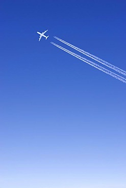 One single passenger jet with condensation trail white in blue sky