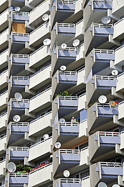 Woman standing in a residential building with balconies and satellite dishes, Chorweiler near Cologne, North Rhine-Westphalia, Germany, Europe