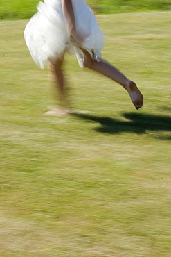 Young woman runs in a white dress without shoes over a meadow